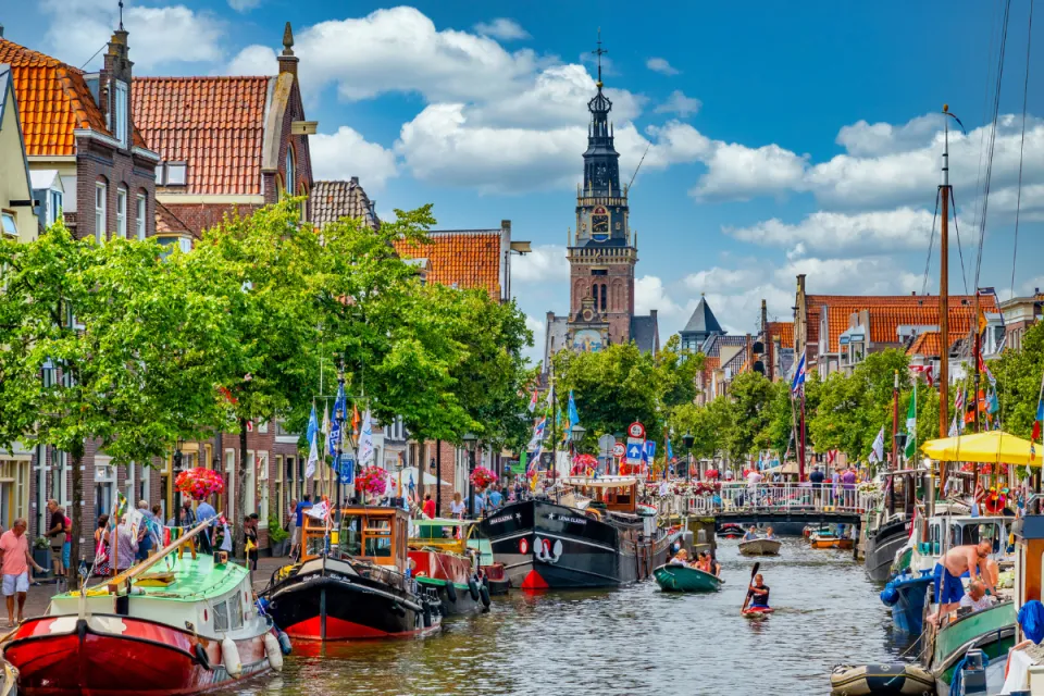 Gracht in Alkmaar met aangemeerde boten en de Waagtoren op de achtergrond